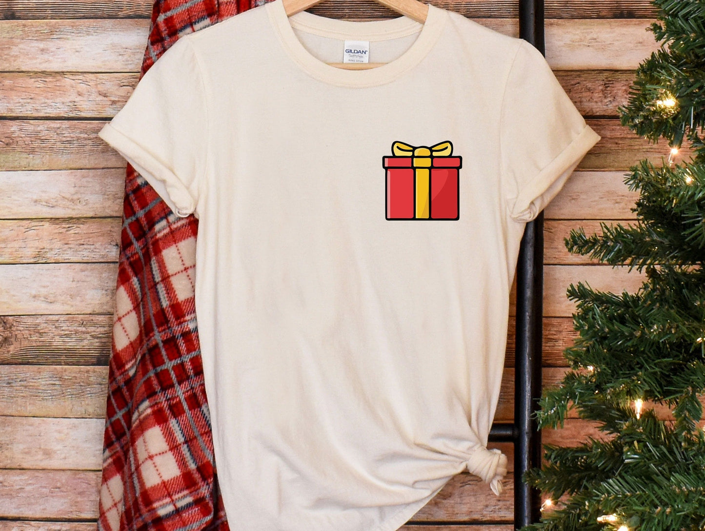 a t - shirt with a present on it next to a christmas tree