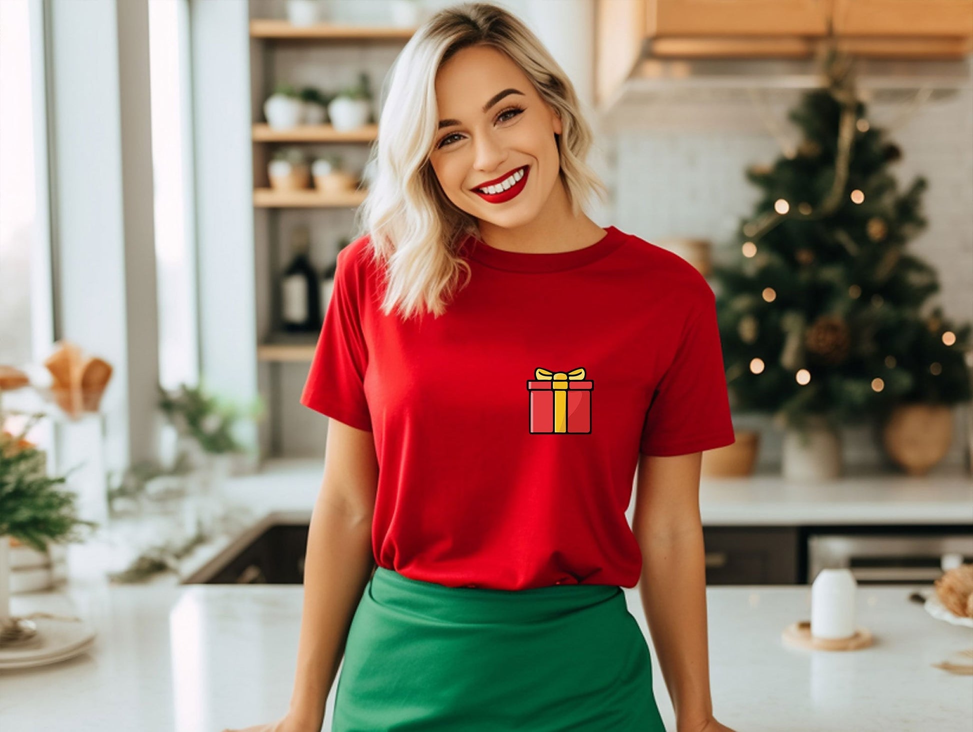 a woman standing in a kitchen wearing a red shirt with a present on it