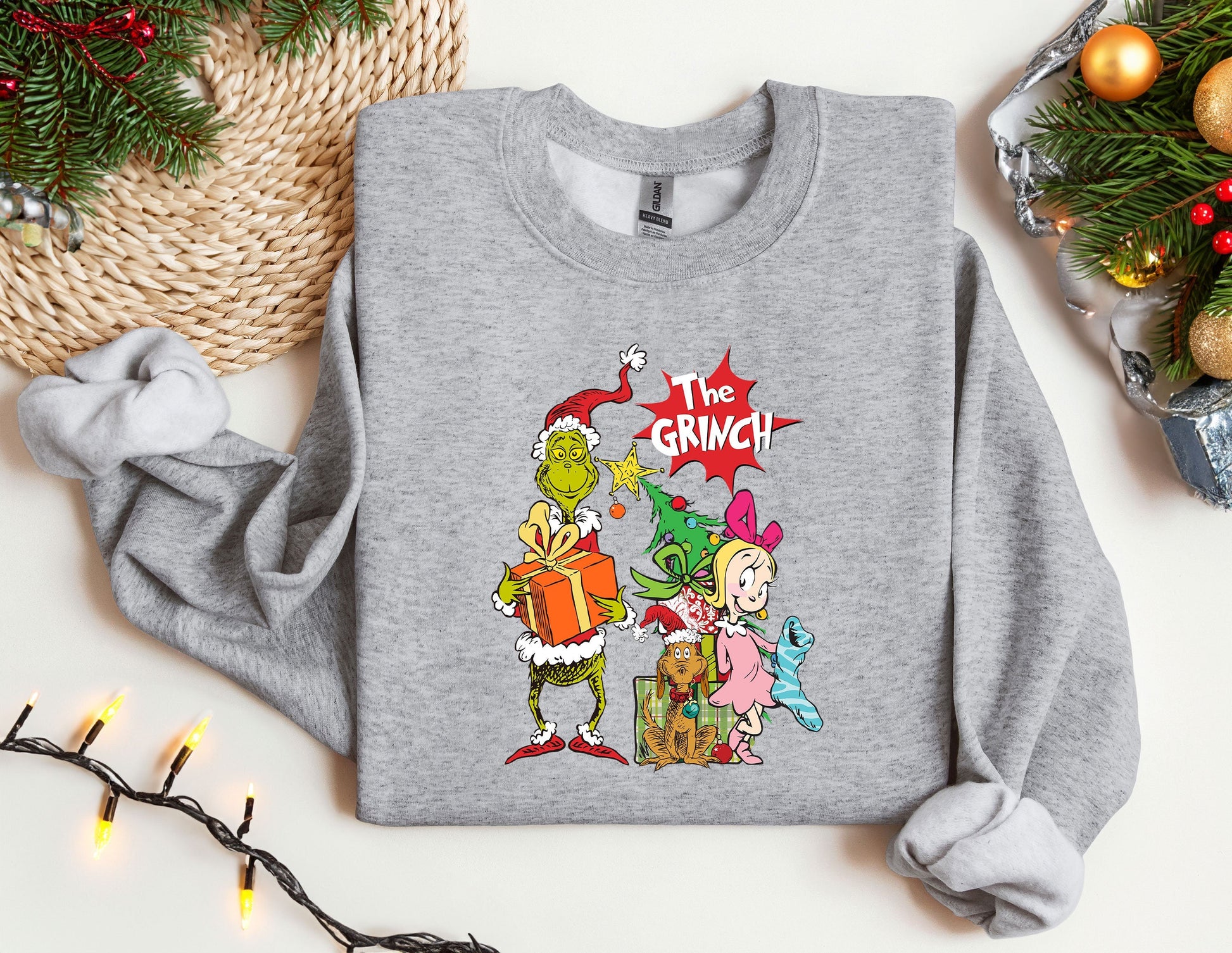 a grey sweatshirt with the grinch on it next to a christmas tree